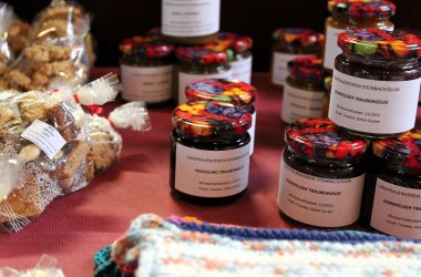 Gläser mit dunkler Marmelade und Gebäck an einem Weihnachtsmarktstand.