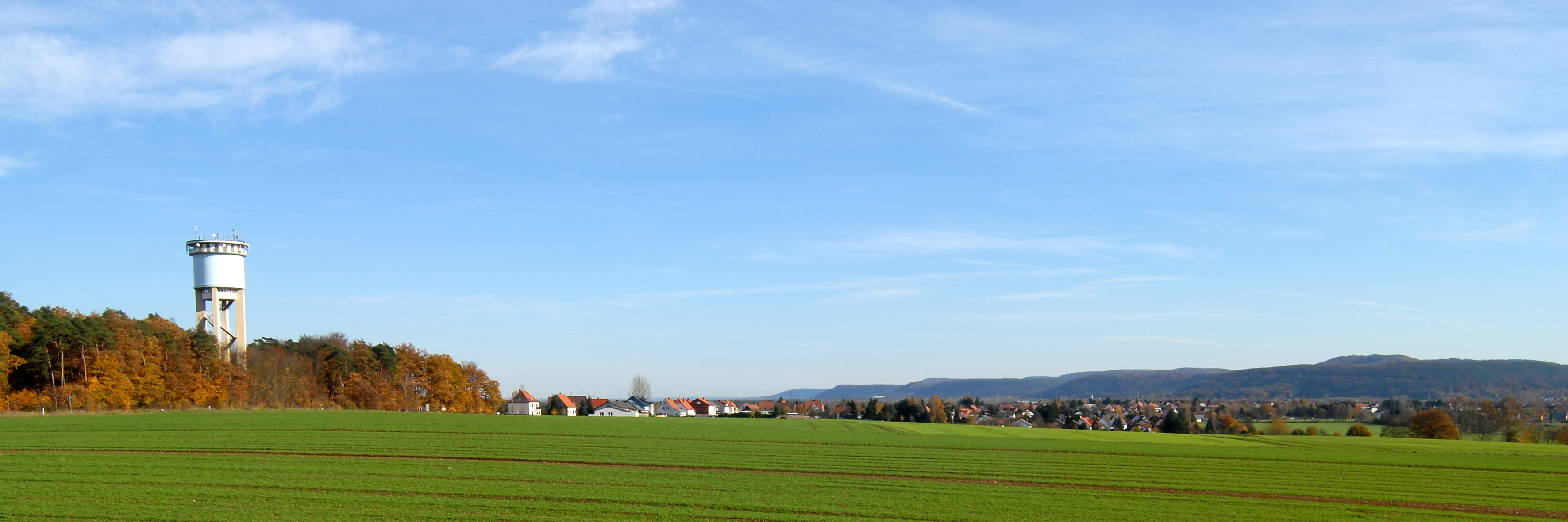 Miesau Wasserturm Lings ein Wasserturm im Wald. Davor ein Feld und daneben ein Dorf.