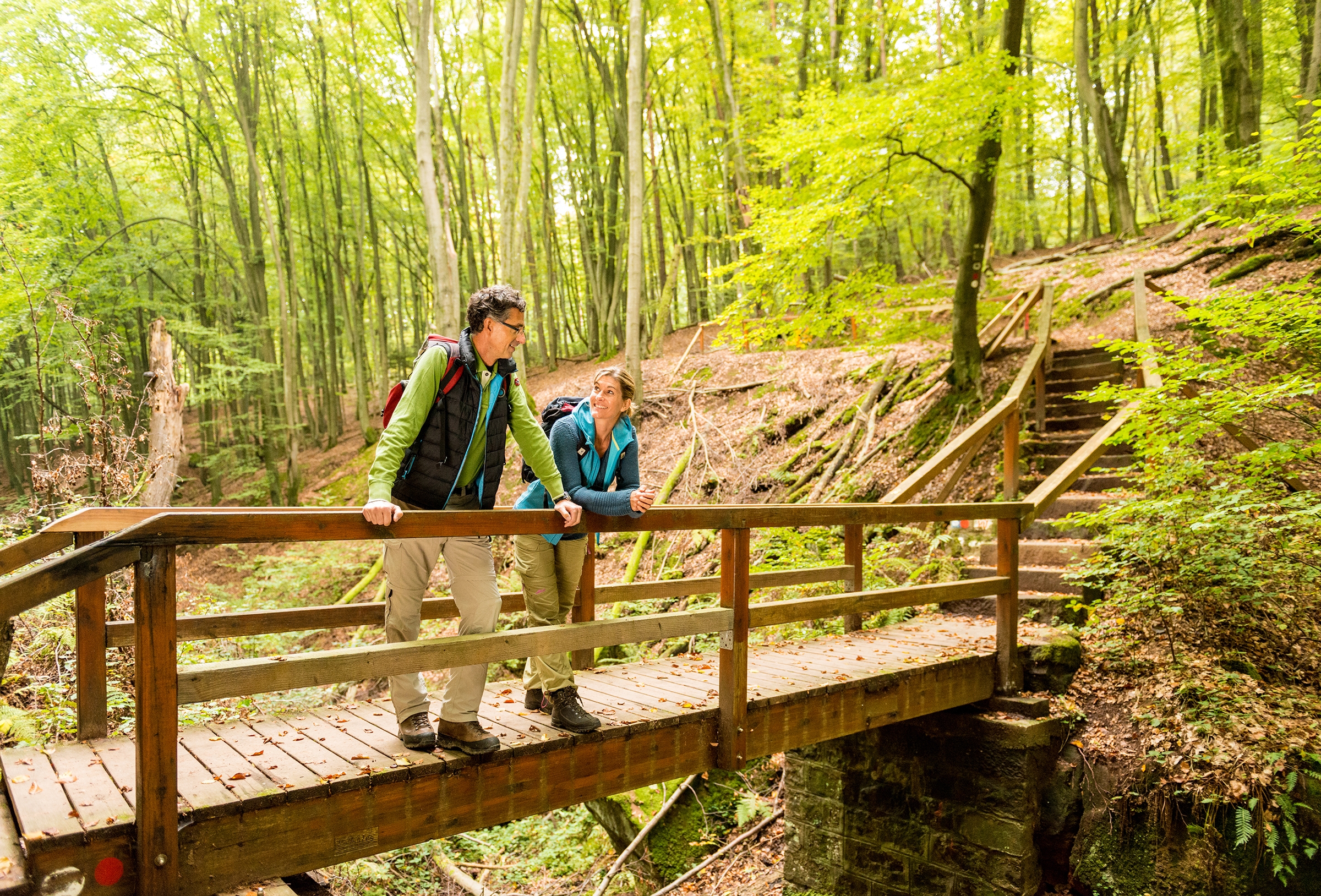 Sagenhafter Waldpfad Zwei Wanderer auf einer Brücke im Wald
