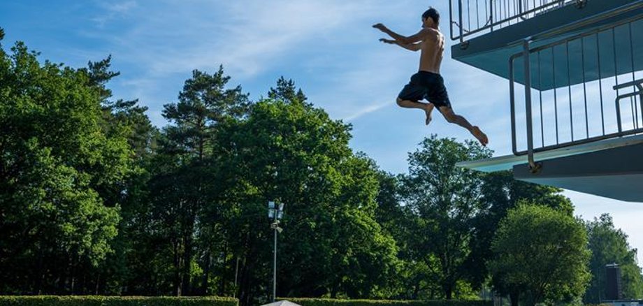 Freibad Junge der vom Sprungturm ins Schwimmbecken springt.