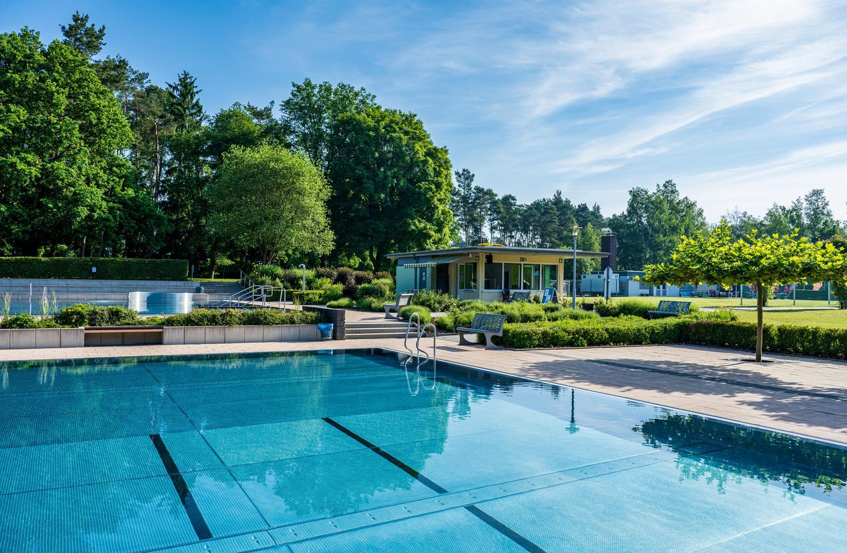 Schwimmbecken mit Kiosk im Hintergrund
