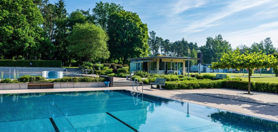 Schwimmbecken mit Kiosk im Hintergrund